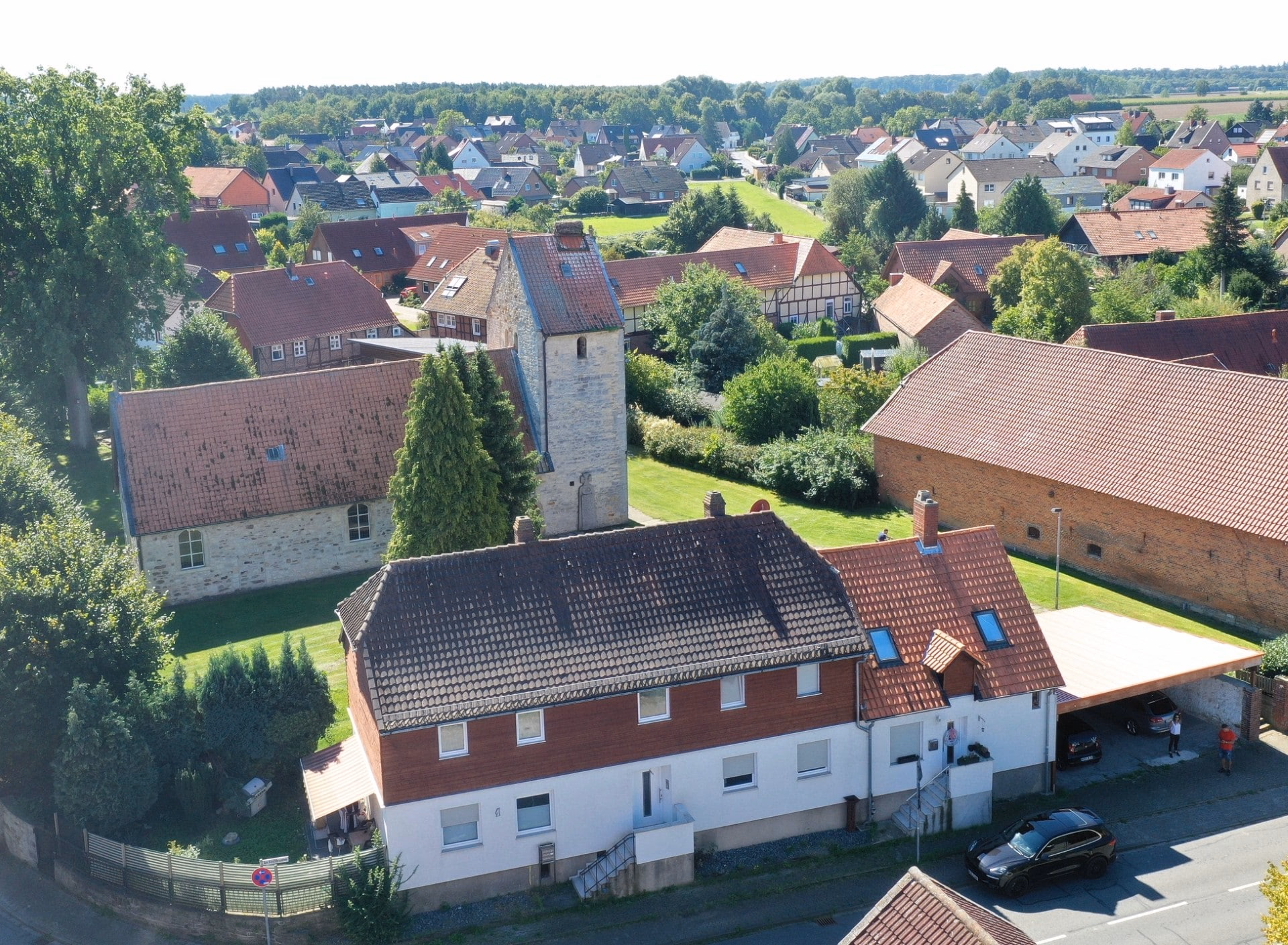 Luftaufnahme des Wohnhauses Am Kirchbrunnen 1 mit Kirche im Hintergrund