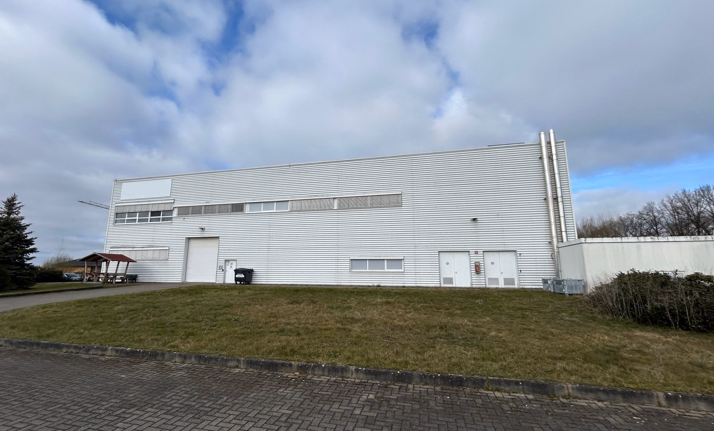 Seitenansicht der Halle mit Rolltor und Grünflächen