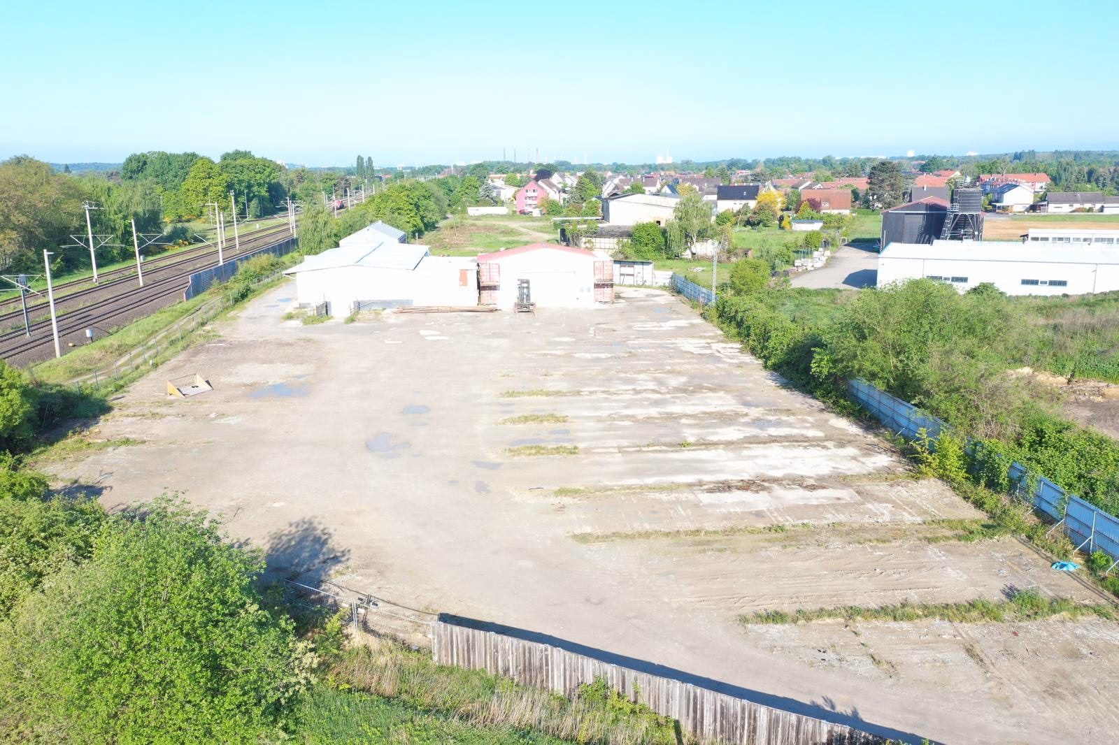 Drohnenaufnahme der Freifläche mit Hallen und Bahnstrecke